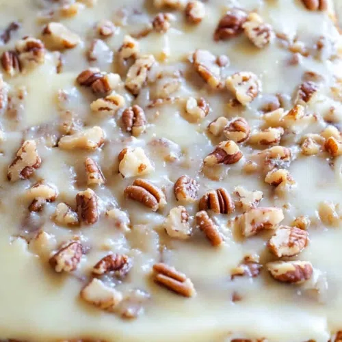A whole cake with a golden-brown top and pecan garnish.