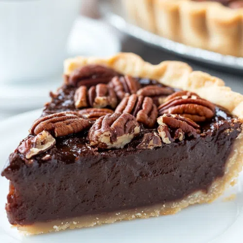 A pie slice on a plate, showing layers of chocolate and pecan filling.
