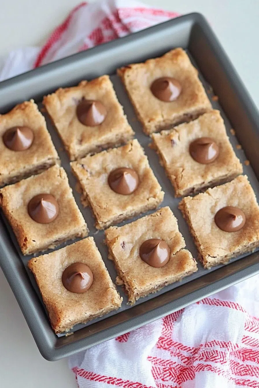 A batch of golden cookie bars with a chocolate piece nestled in the center.