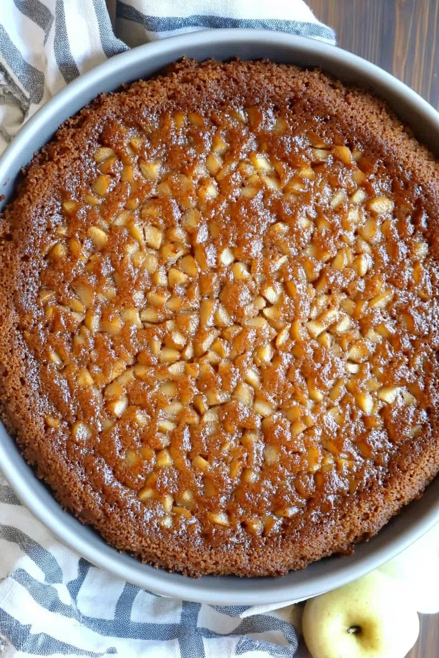 Whole Swedish apple cake garnished with a sprinkle of cinnamon.