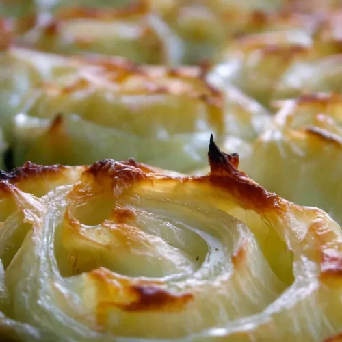 Close-up of caramelized onions with a cheesy topping, fresh from the oven.