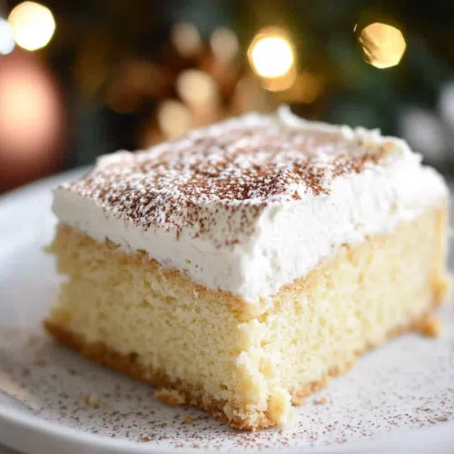 Close-up of a creamy, spiced cake with visible poke holes filled with sweet glaze.