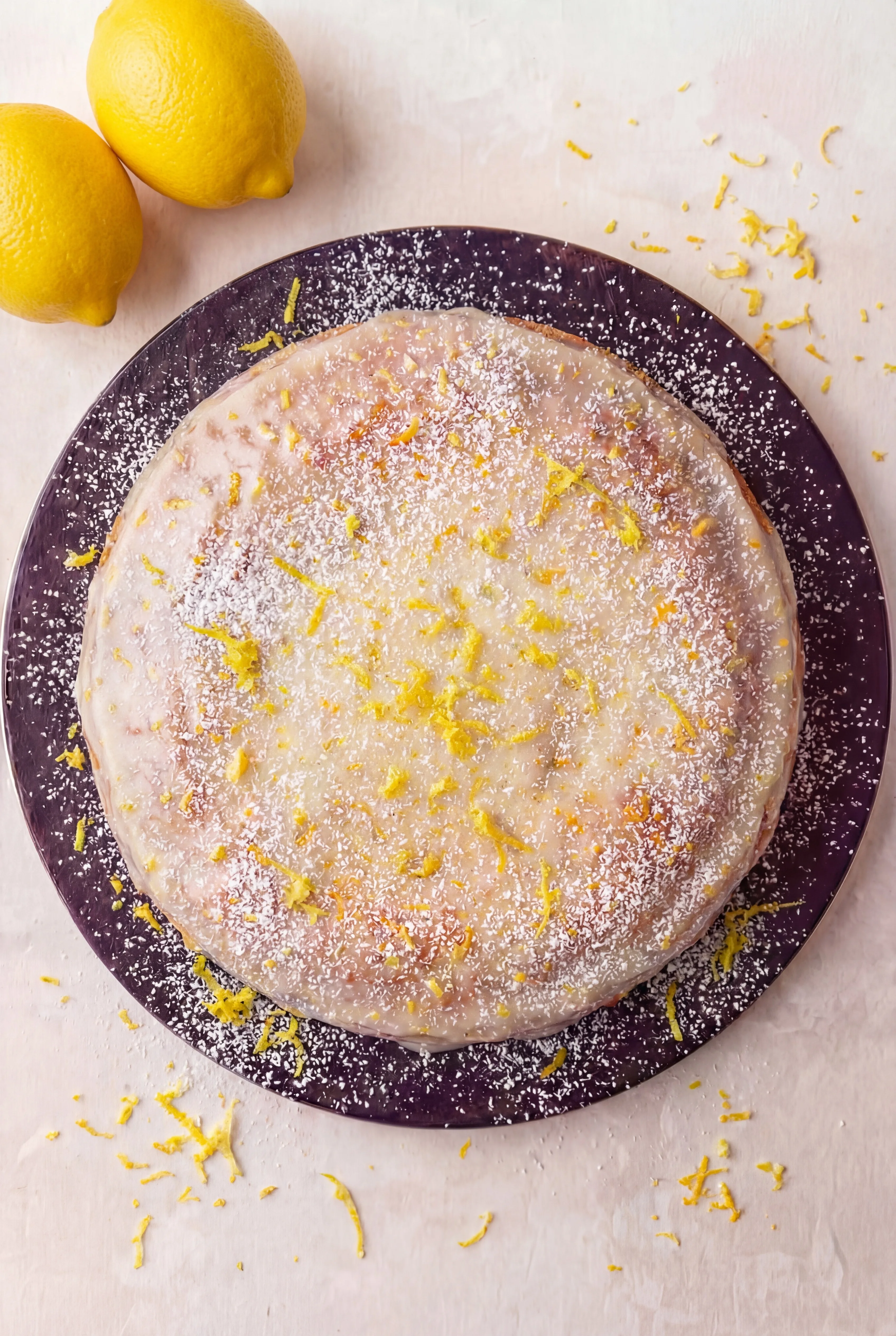 Limoncello Ricotta Cake topped with lemon glaze, powdered sugar, and fresh lemon zest