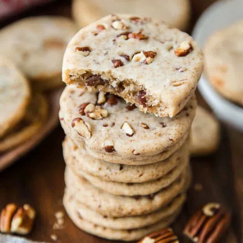 Several baked treats styled on a rustic plate with chopped pecans nearby.