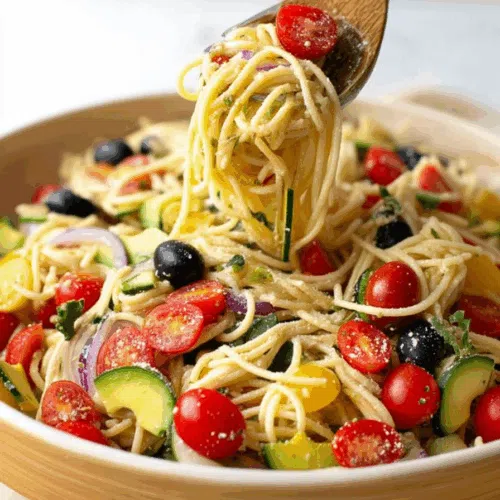 Colorful bowl filled with rotini, fresh vegetables, and dressing.