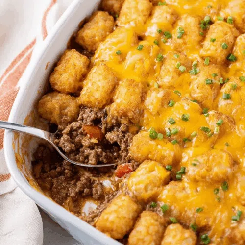 Close-up of crispy tots nestled into a rich, hearty base.