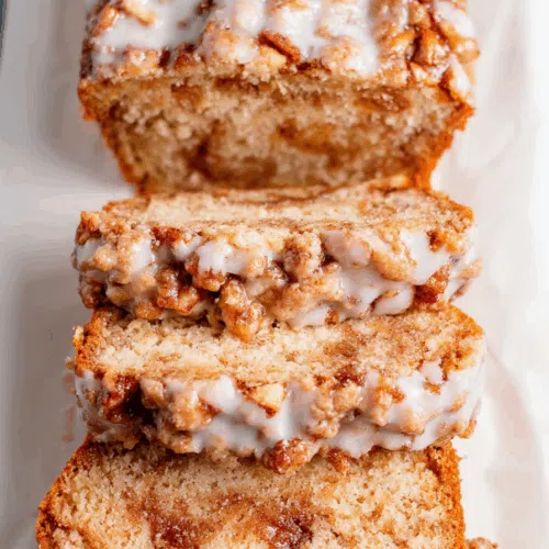 Sliced sweet bread showing chunks of apple and swirls of cinnamon throughout.