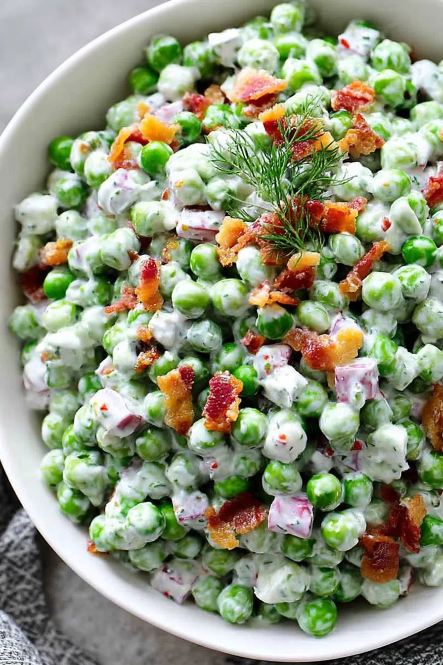 Overhead shot of a chilled salad served in a white bowl, topped with crispy bacon bits.