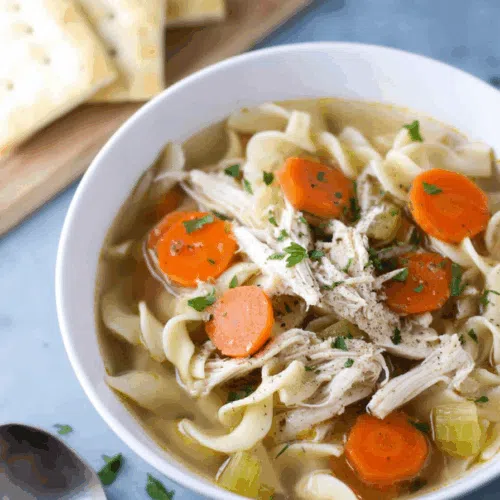 Comforting bowl of warm soup served with a spoon and fresh herbs on top.