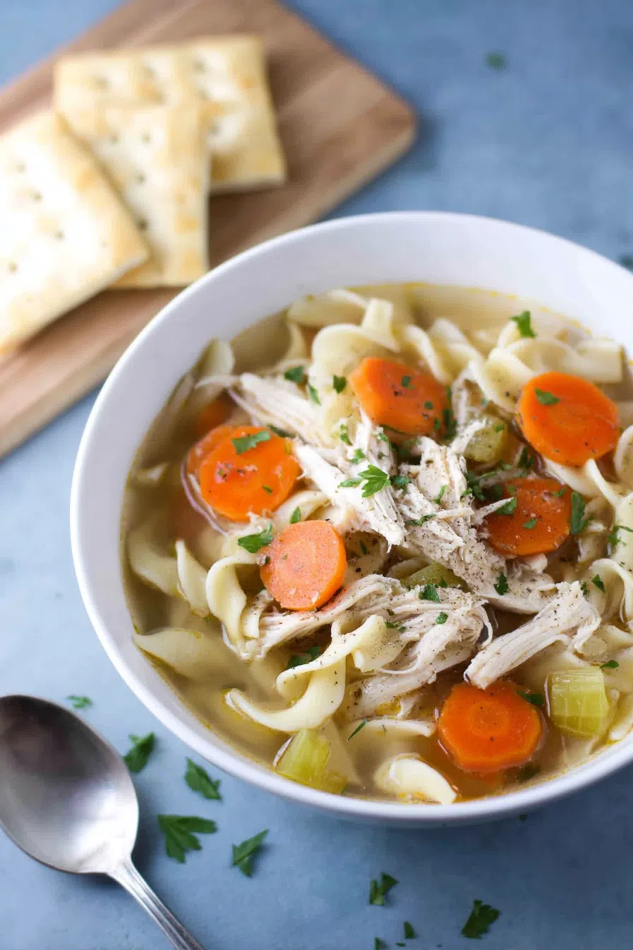 Comforting bowl of warm soup served with a spoon and fresh herbs on top.