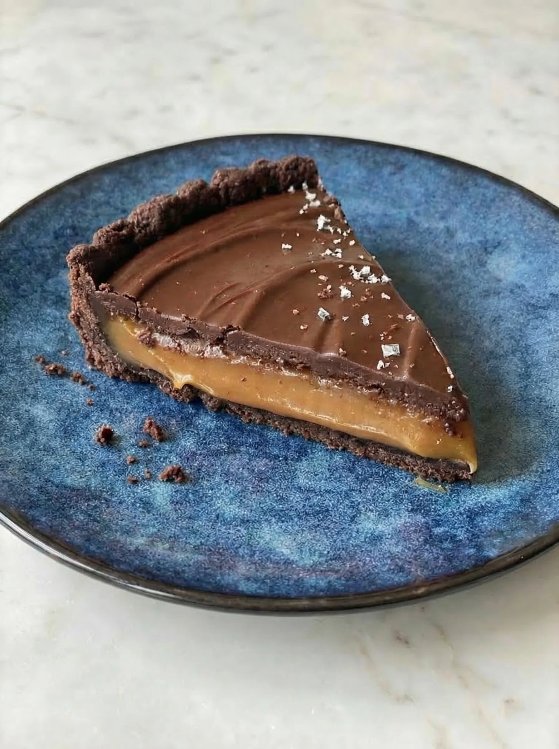 Close-up of tart slice showing rich caramel layer and chocolate ganache
