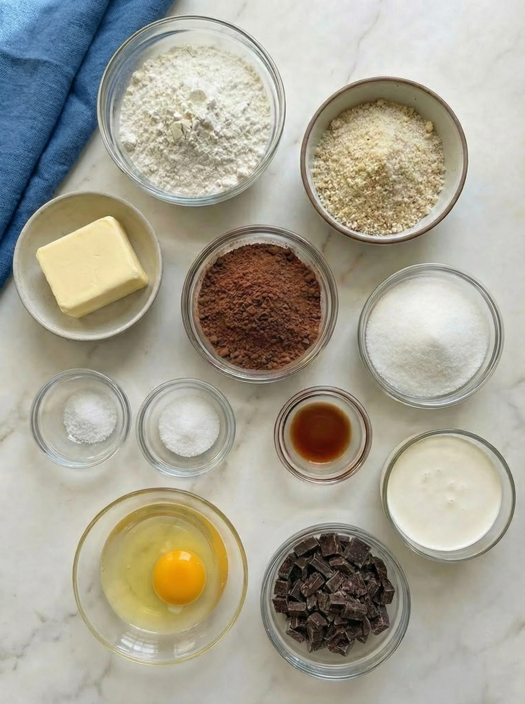 Ingredients for chocolate tart including cocoa powder, flour, butter, sugar, eggs, vanilla, chocolate, and cream