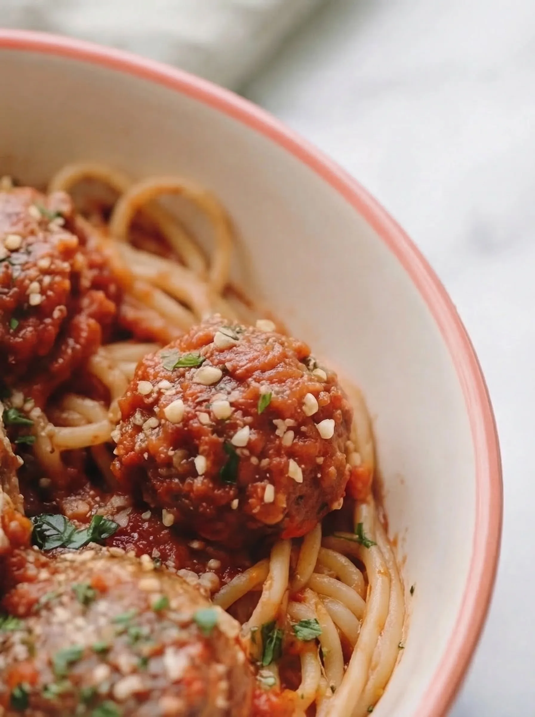 Close-up of tender meatballs coated in tomato sauce and sprinkled with parmesan