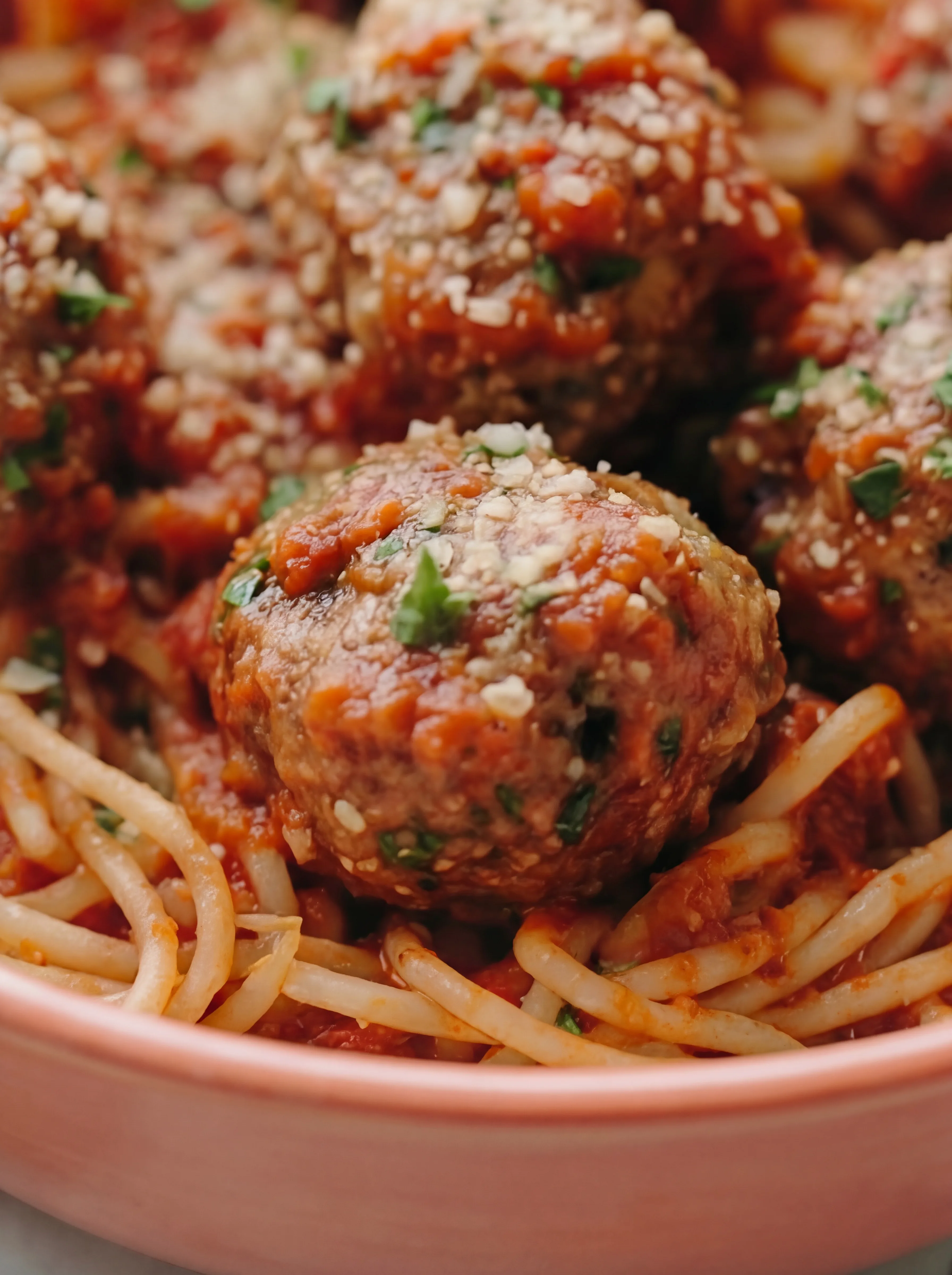 Close-up of Classic Italian Meatballs over spaghetti coated in rich tomato sauce and topped with grated parmesan and fresh herbs