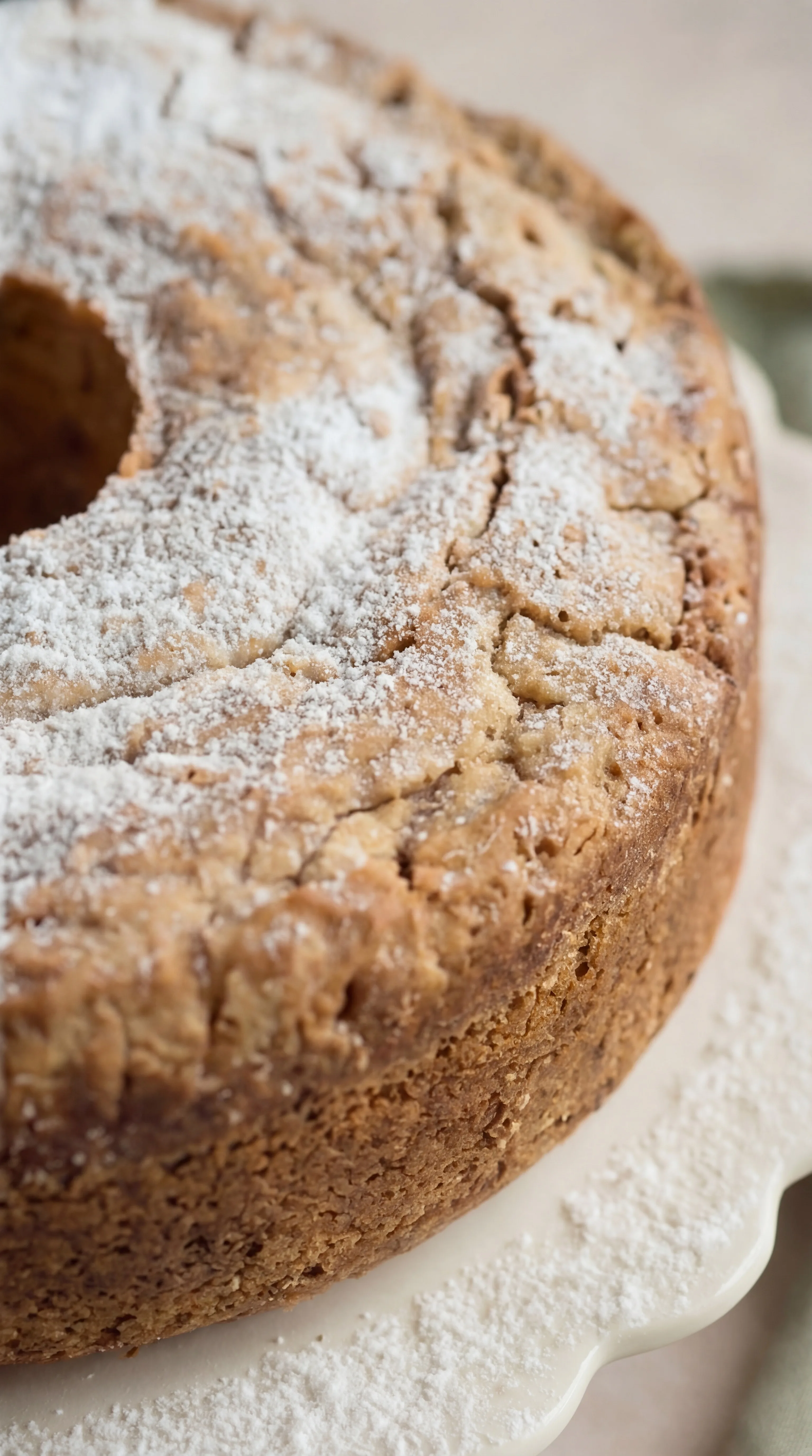 powdered sugar topping on baked coconut cream cheese pound cake with cracked golden crust