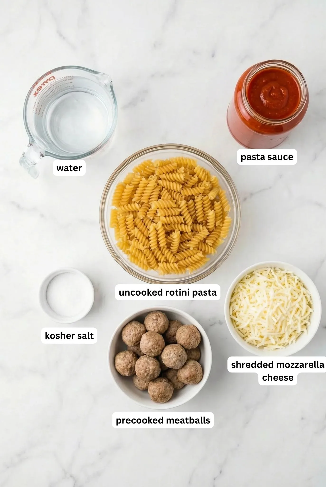 Ingredients for dump and bake meatball casserole including uncooked rotini pasta, pasta sauce, water, precooked meatballs, shredded mozzarella cheese, and kosher salt