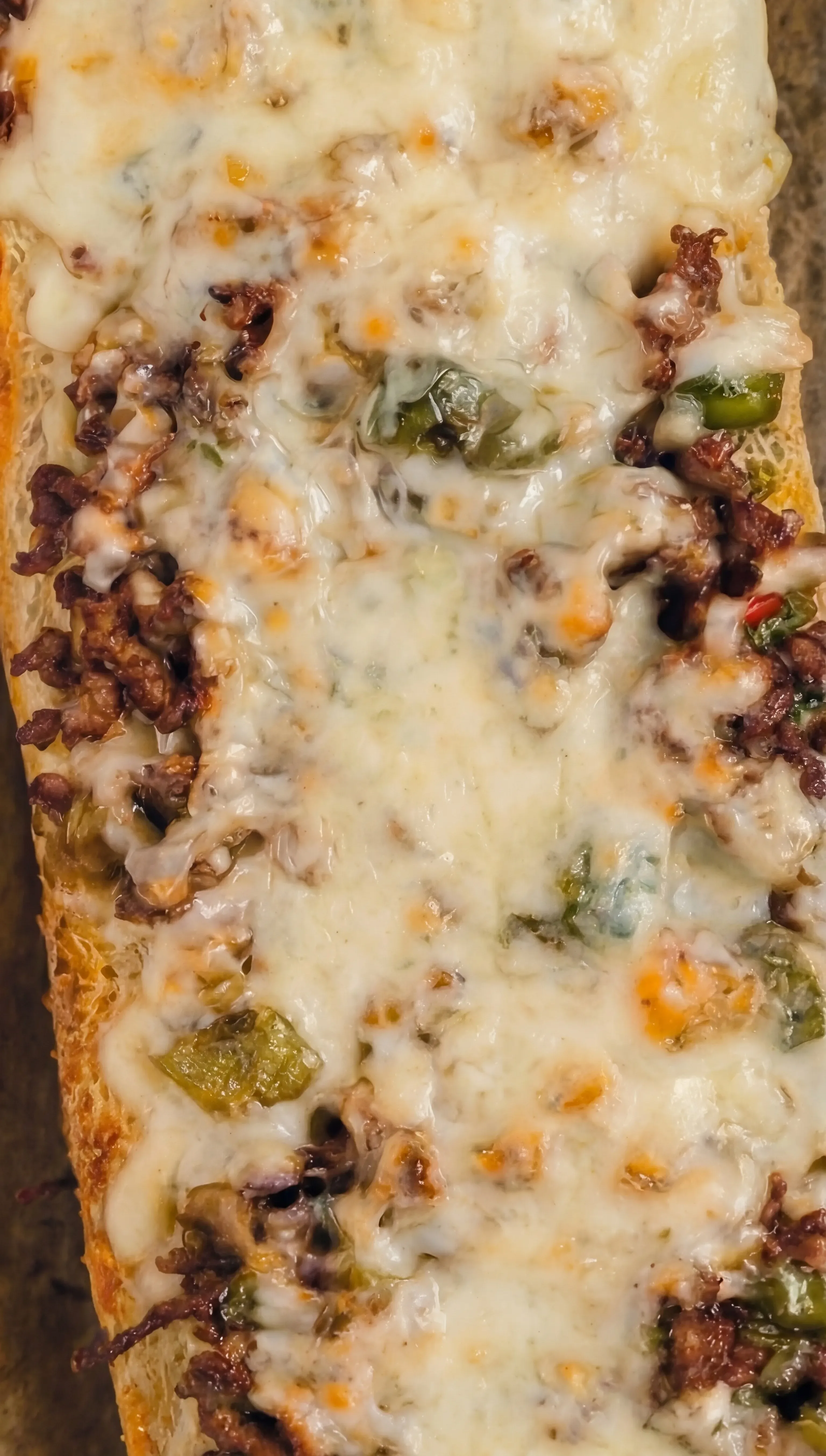 Loaded Cheesesteak Cheesy Bread showing melted cheese, seasoned beef, peppers, and mushrooms