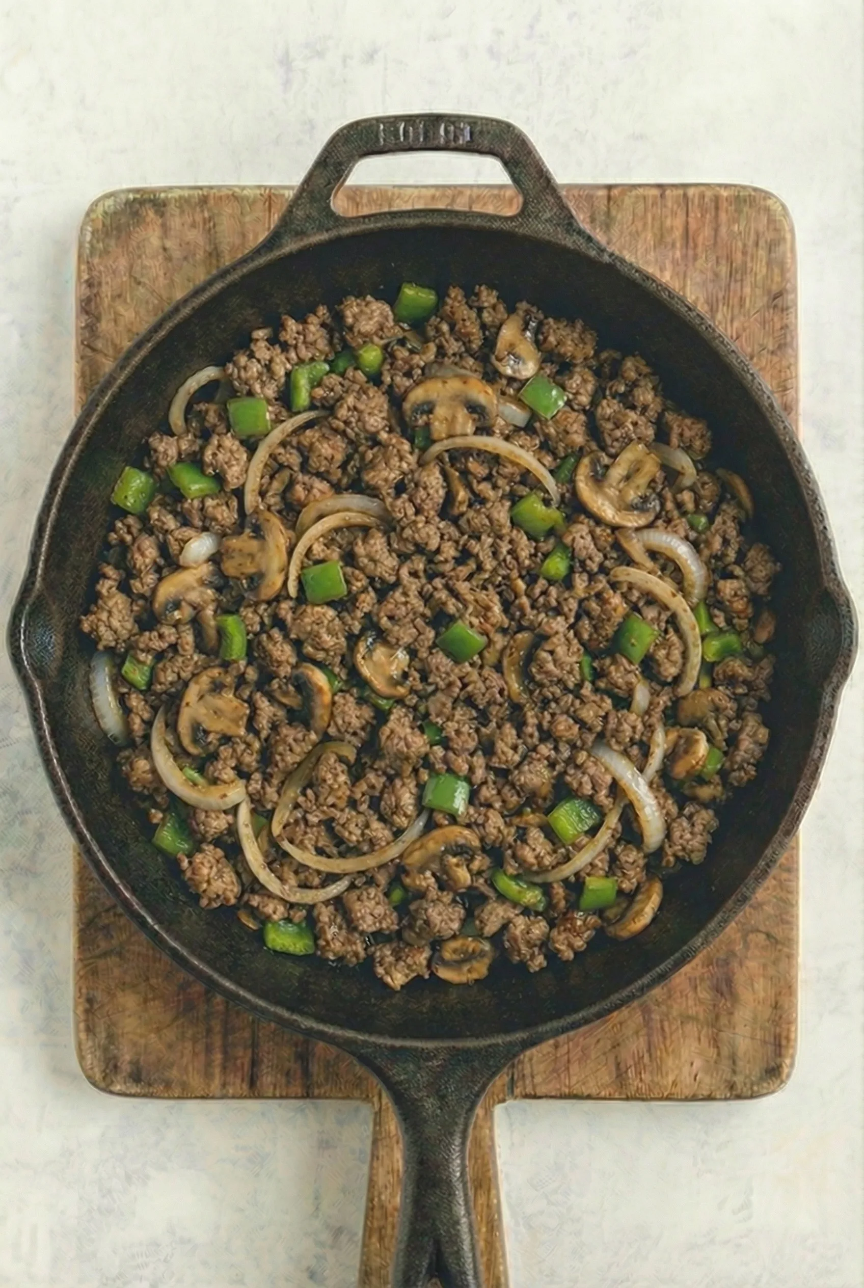 ground beef cooked with mushrooms, onions, and green peppers in skillet for cheesesteak cheesy bread filling