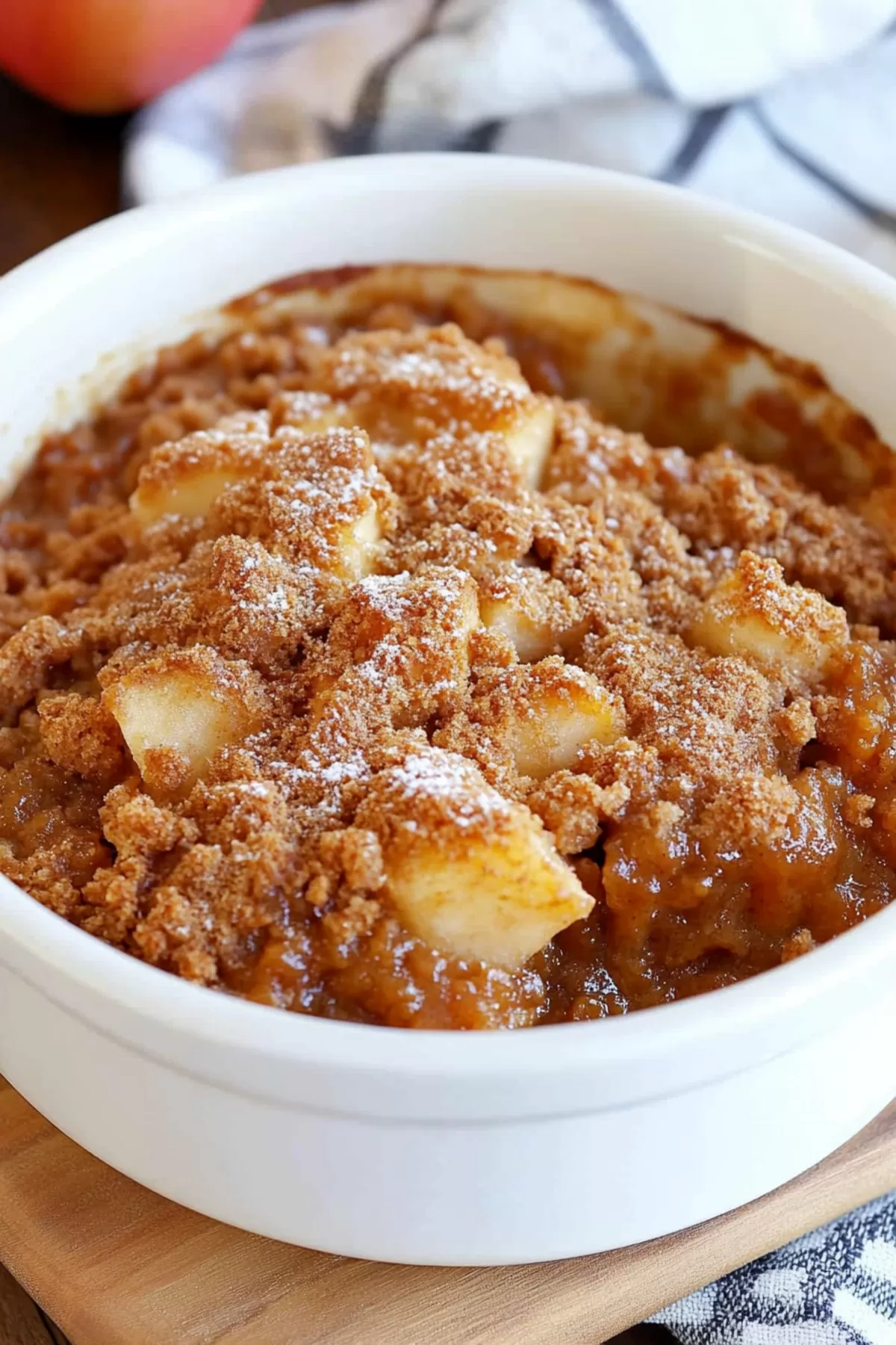 Individual portion of Apple Brown Betty with a dusting of powdered sugar in a white bowl.