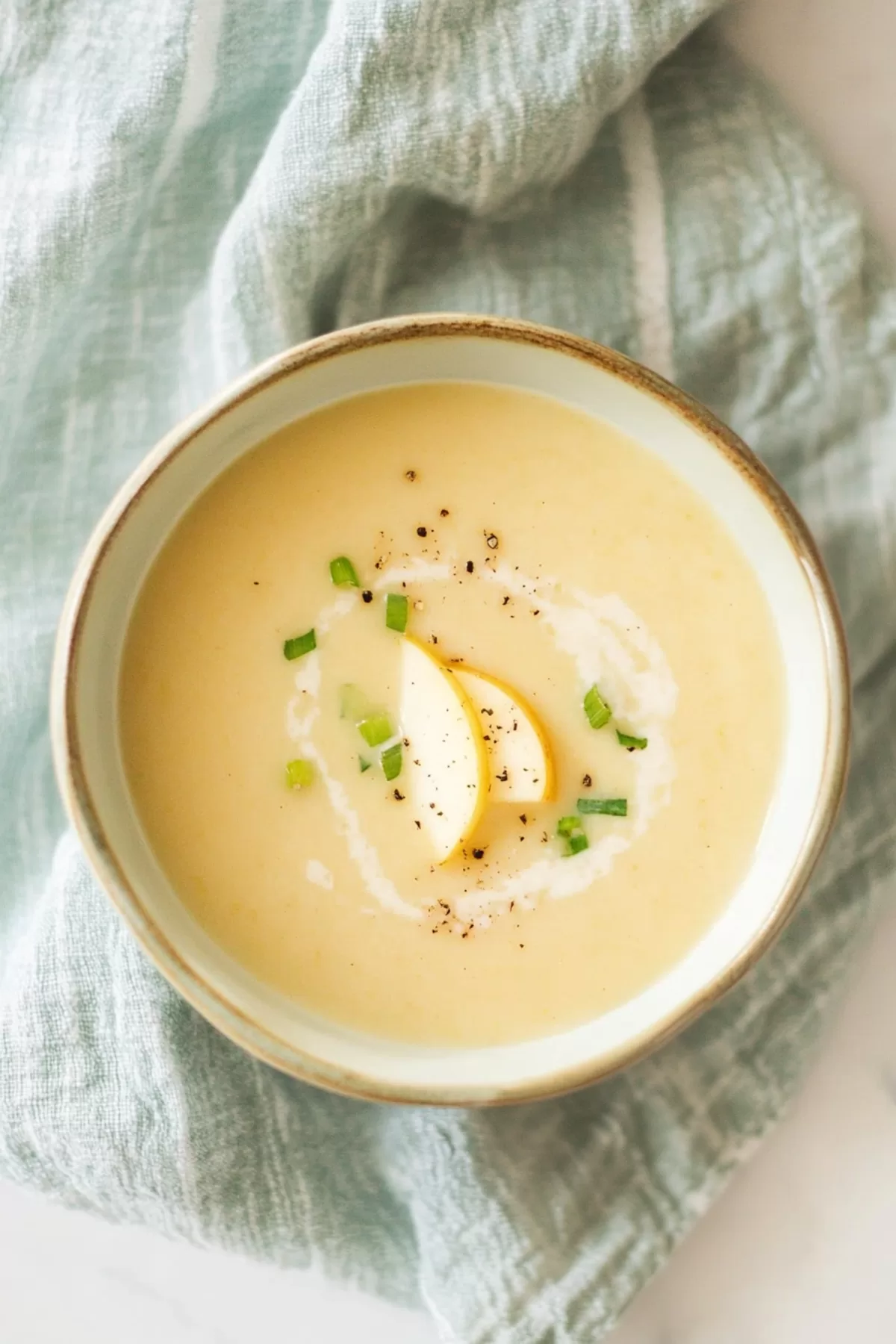 Soup served in an elegant bowl, topped with a swirl of cream and a sprig of thyme.