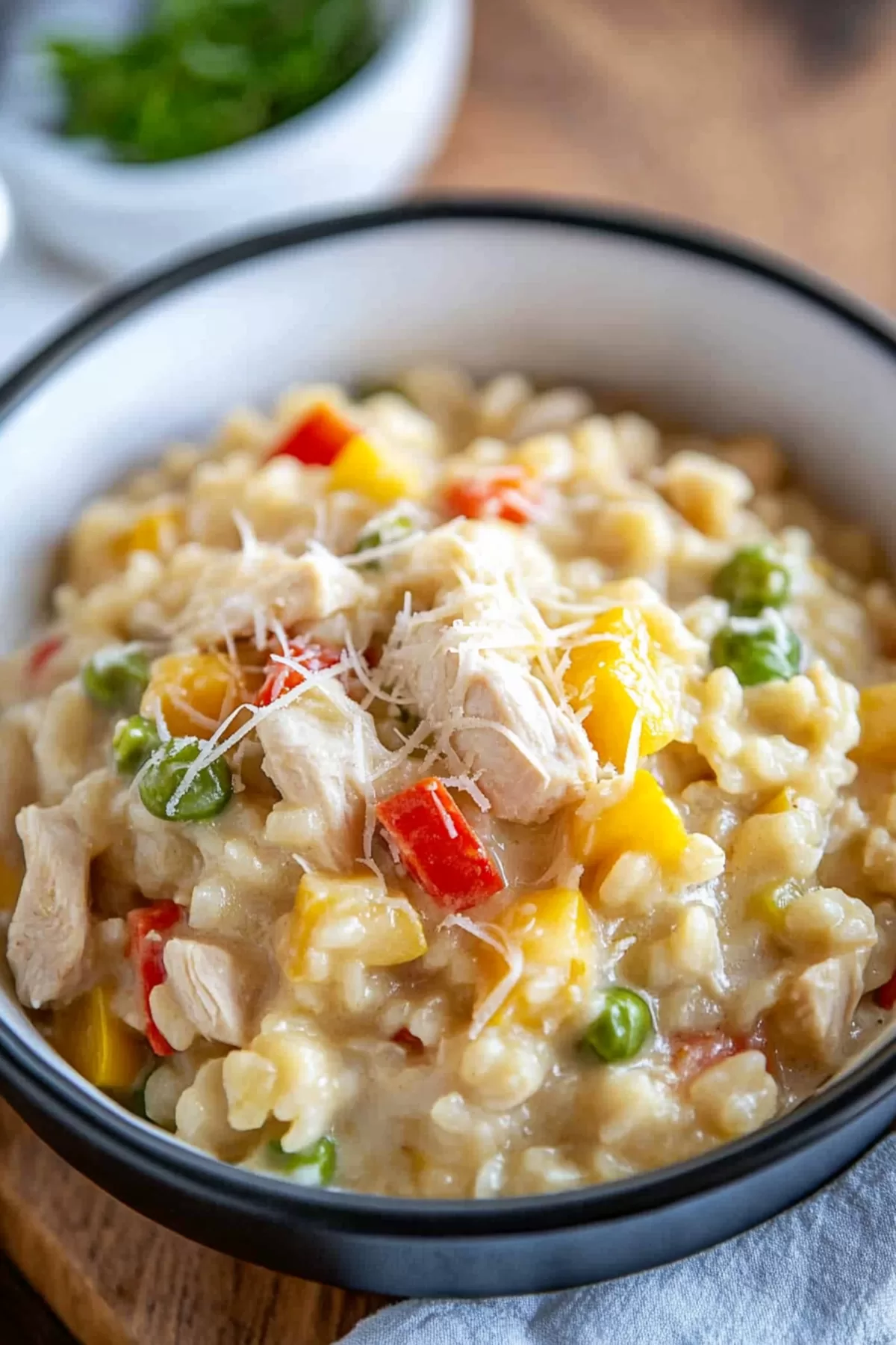 A vibrant bowl of creamy risotto topped with colorful veggies and tender chicken pieces.