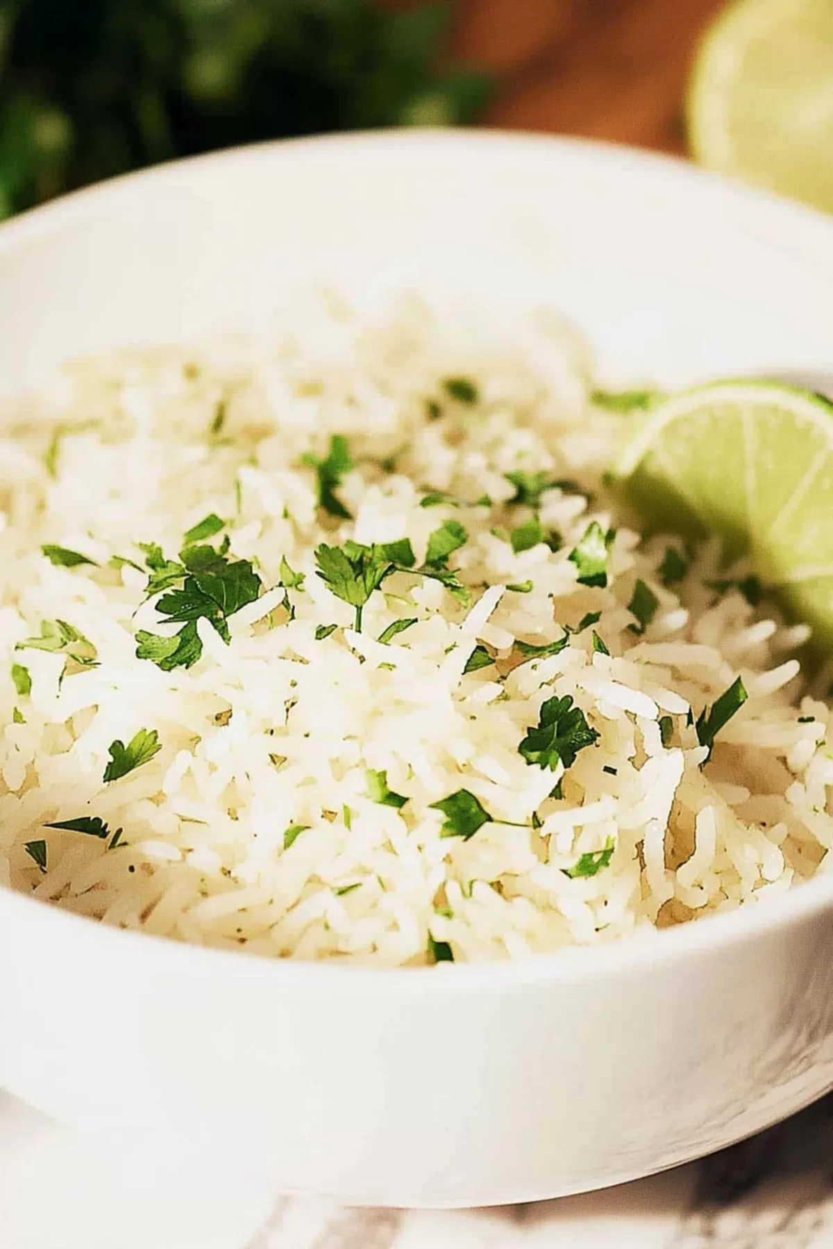 A bowl of fluffy, perfectly cooked rice garnished with fresh cilantro and a wedge of lime.