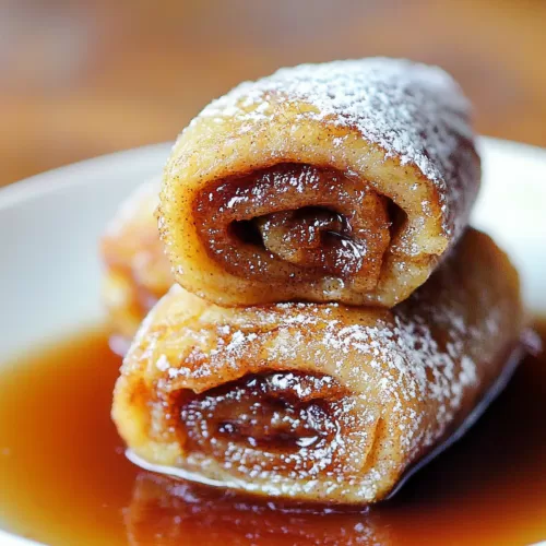 A stack of rolled French toast with a shiny glaze, showcasing their warm, gooey centers.