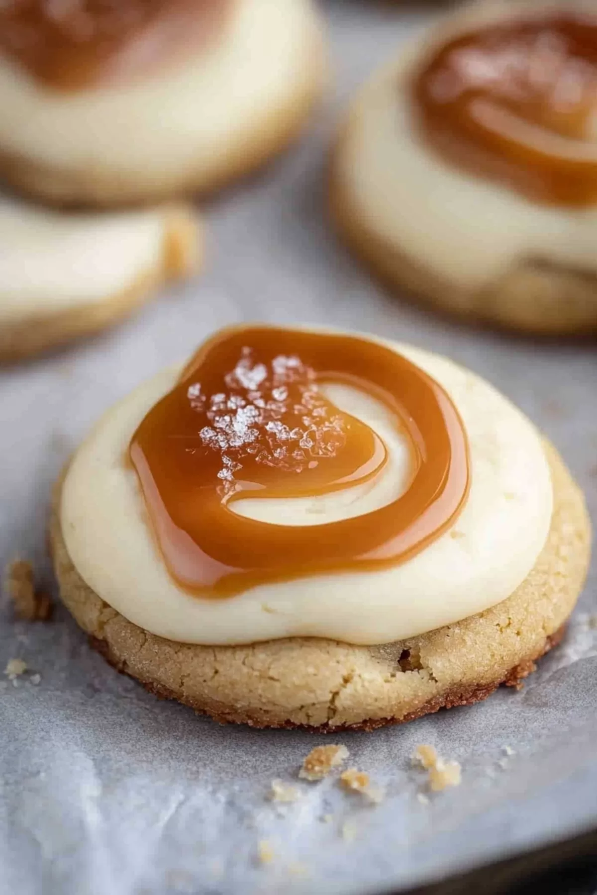 Close-up of a cookie topped with velvety cheesecake frosting and caramel swirls.