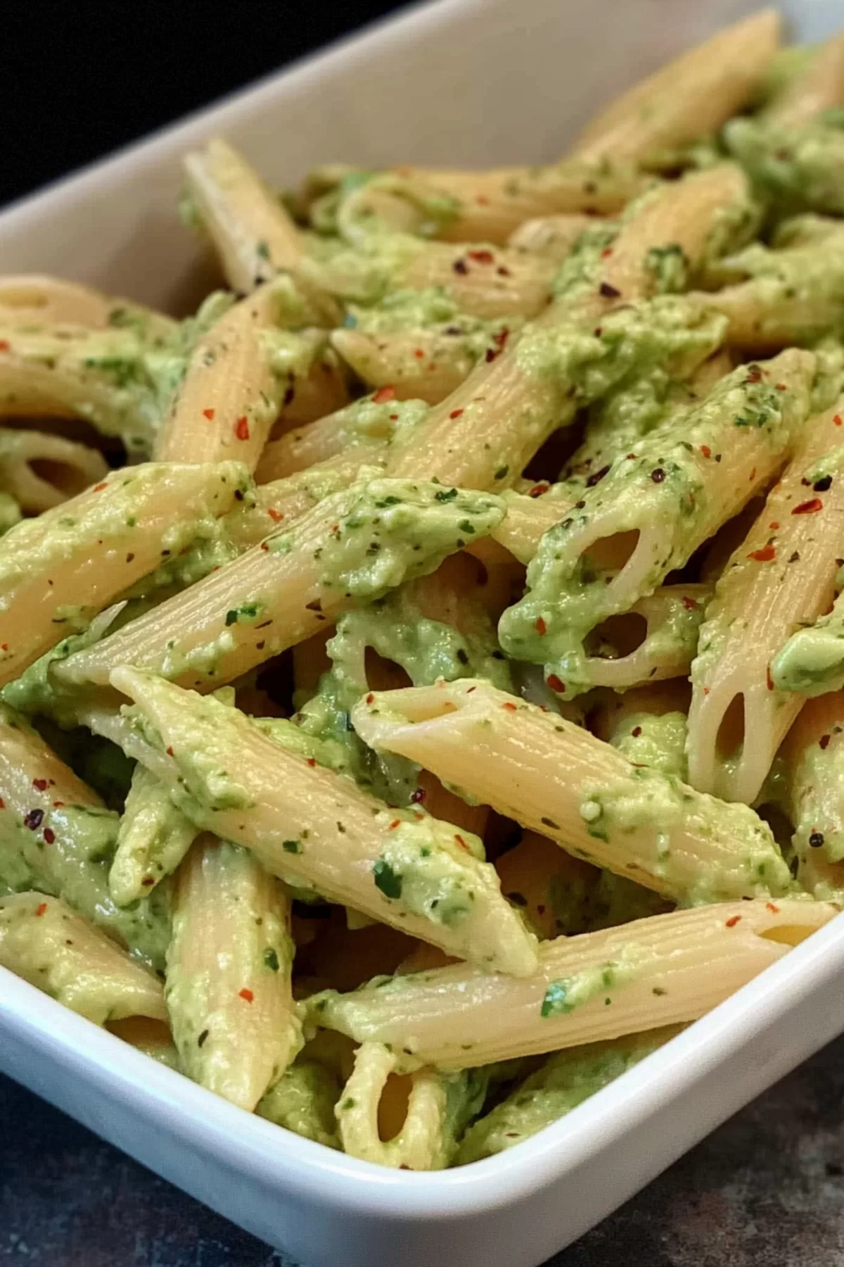 Close-up of spaghetti coated in a smooth, rich avocado sauce with a sprinkle of Parmesan.