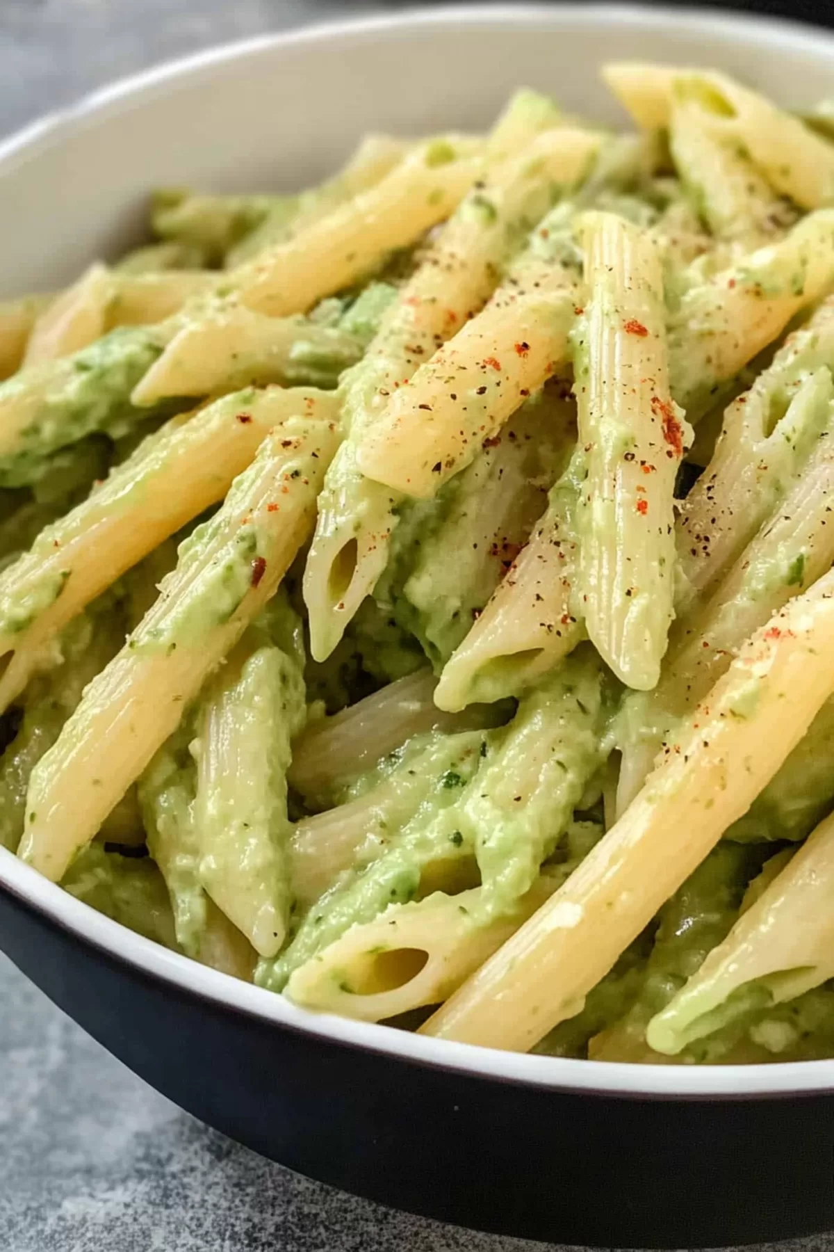 A serving of pasta with a velvety avocado sauce, topped with cherry tomatoes for a pop of color.