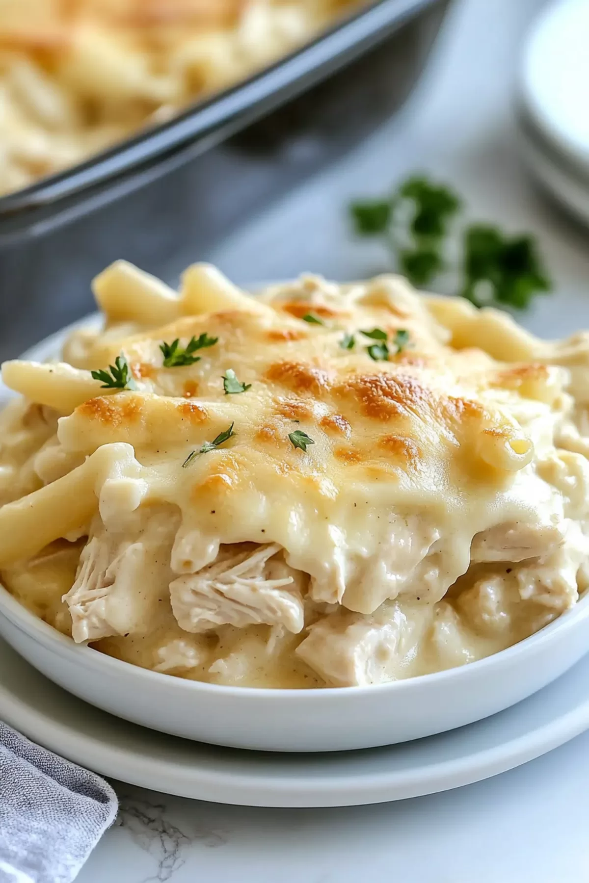 Individual serving of creamy pasta bake on a plate, showing layers of sauce and chicken.