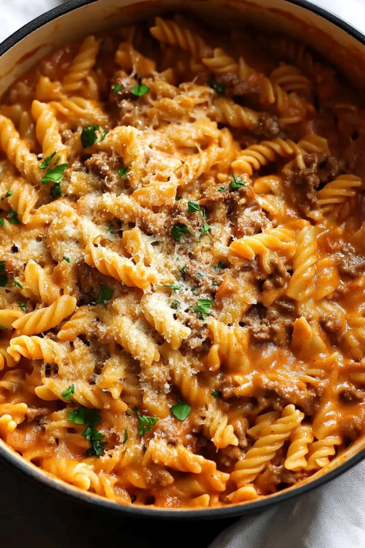 Close-up of twisted rotini pasta coated in a savory mince sauce, served in a cozy bowl.