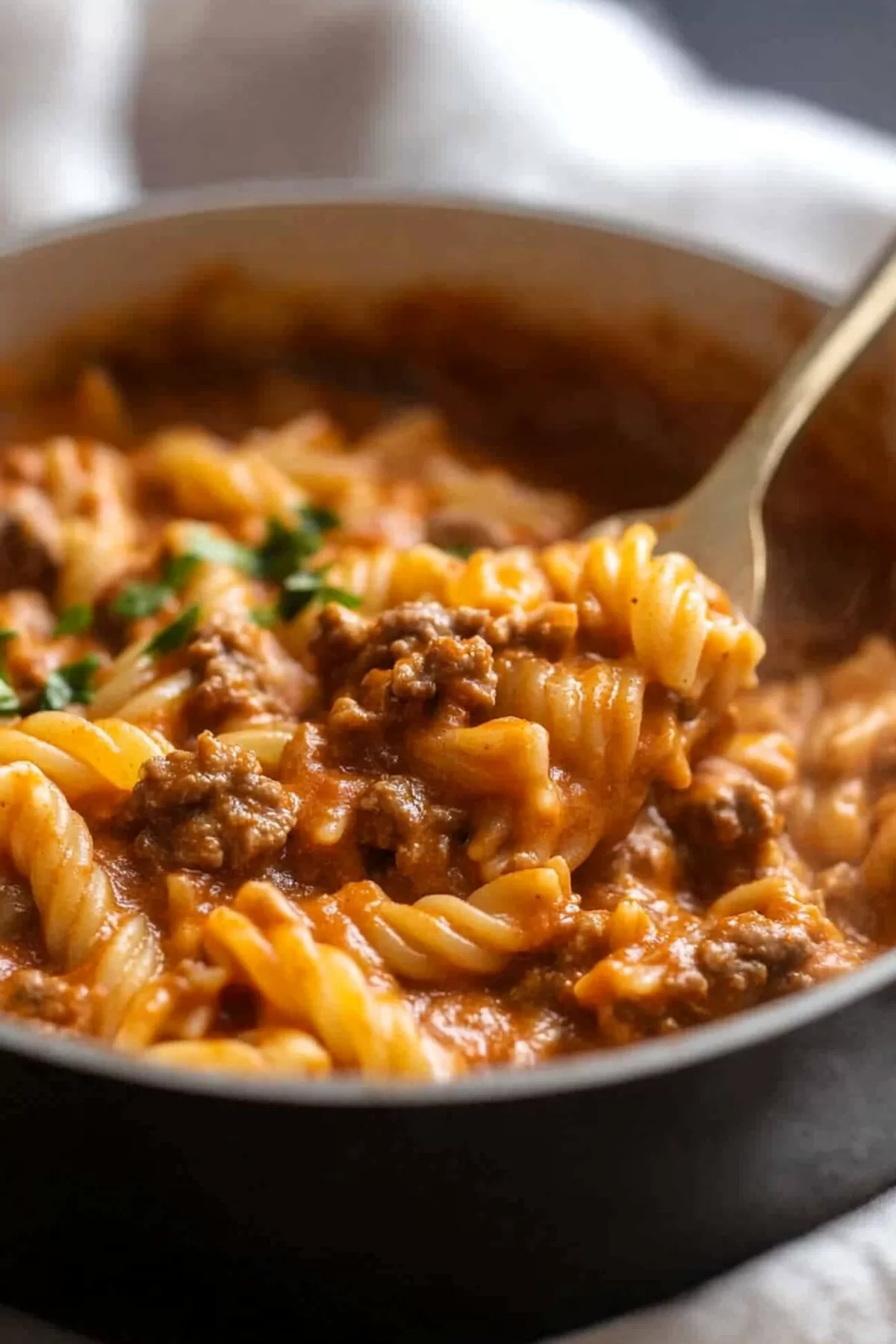 A spoonful of cheesy, saucy pasta with minced meat, ready to be enjoyed for dinner.