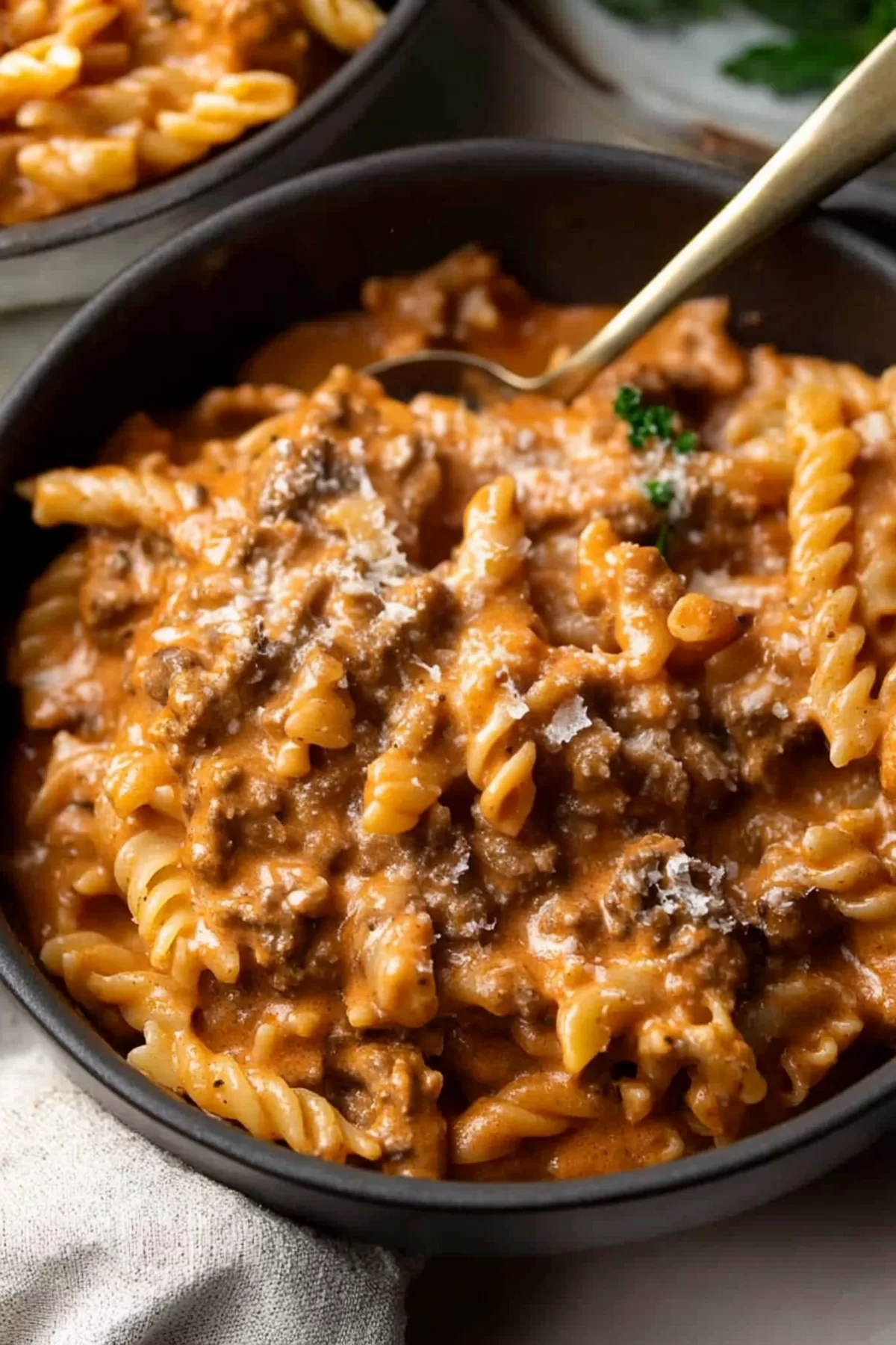 Individual serving of pasta with minced meat sauce, topped with fresh herbs and a sprinkle of cheese for added flavor.