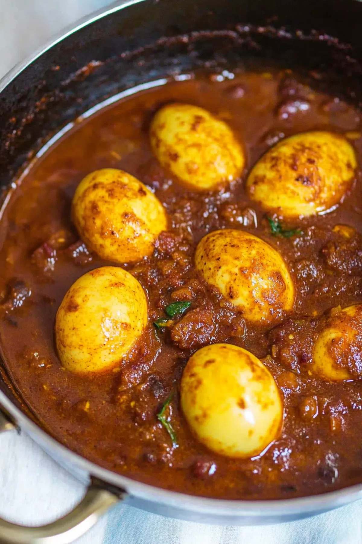 Close-up of creamy curry sauce simmered with whole boiled eggs and aromatic spices.