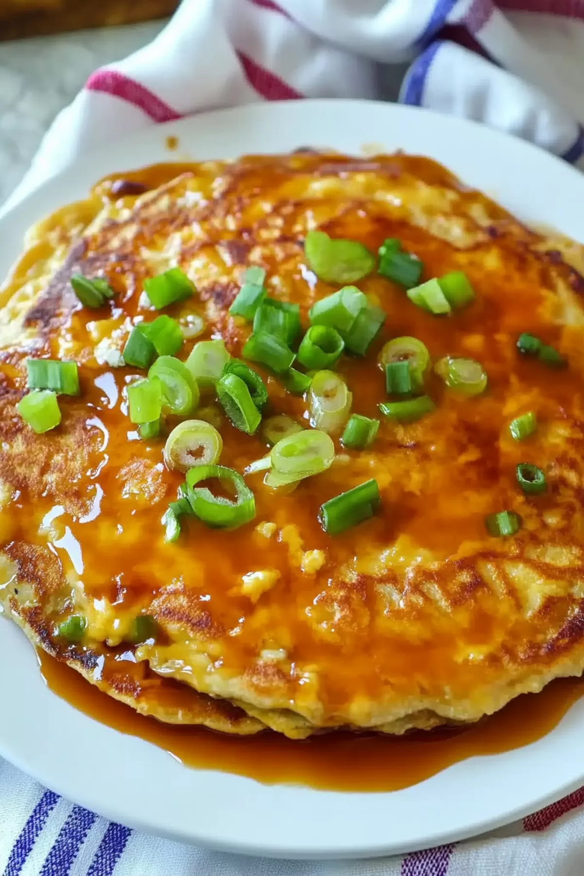 A perfectly cooked Egg Foo Young pancake with crispy edges and a generous drizzle of brown sauce, ready to serve.