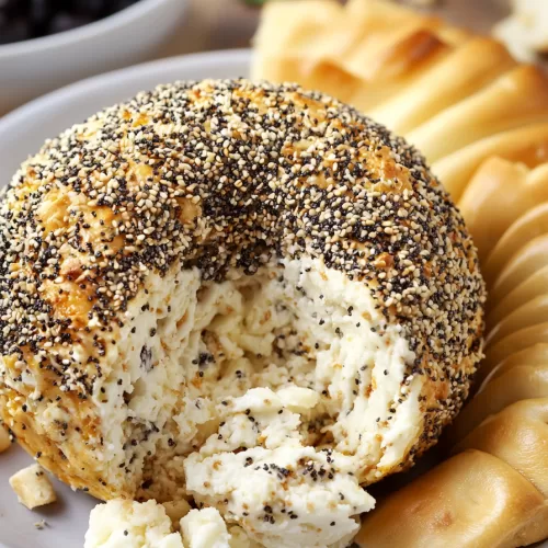 Close-up of a creamy cheese ball covered in poppy seeds, sesame seeds, and garlic flakes.