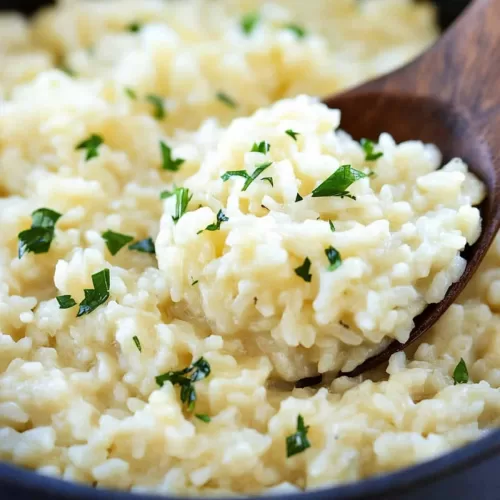 A wooden spoon lifting a portion of creamy risotto, highlighting its rich and cheesy texture.