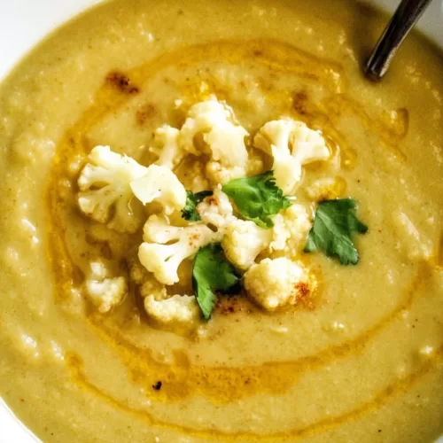 Golden cauliflower soup served with a sprinkle of paprika and fresh herbs for added flavor.