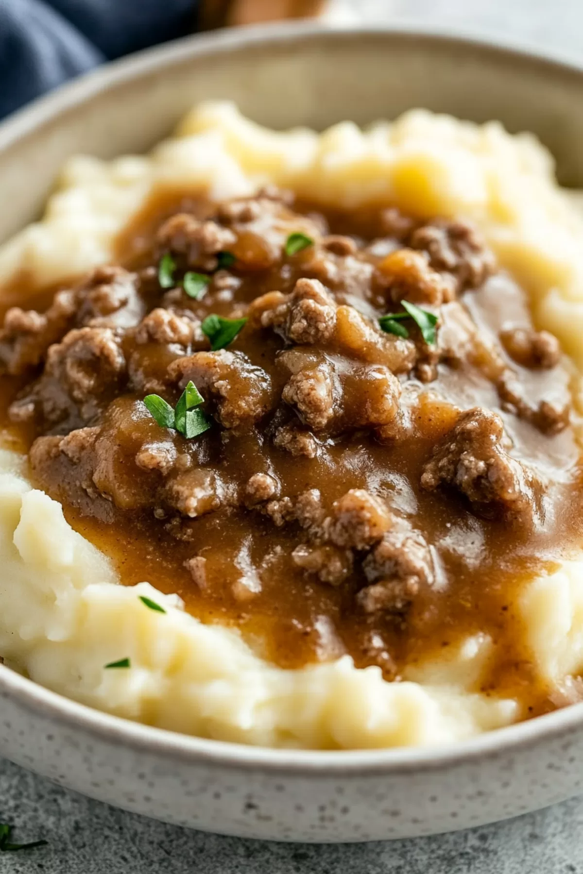 Close-up of mashed potatoes layered with seasoned beef and smooth gravy.