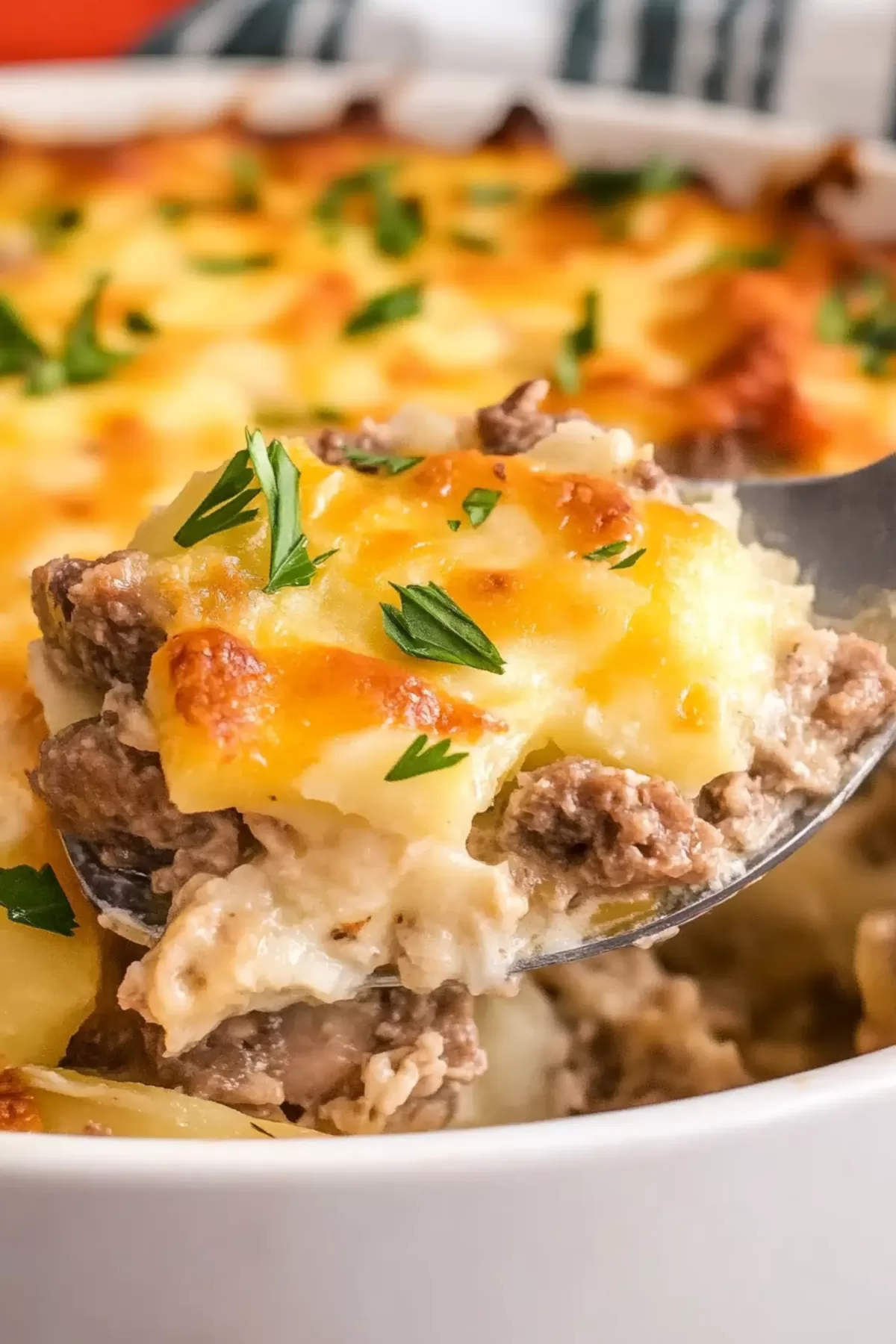 A close-up of a hearty baked casserole with crispy layers and melted cheese served on a white plate.