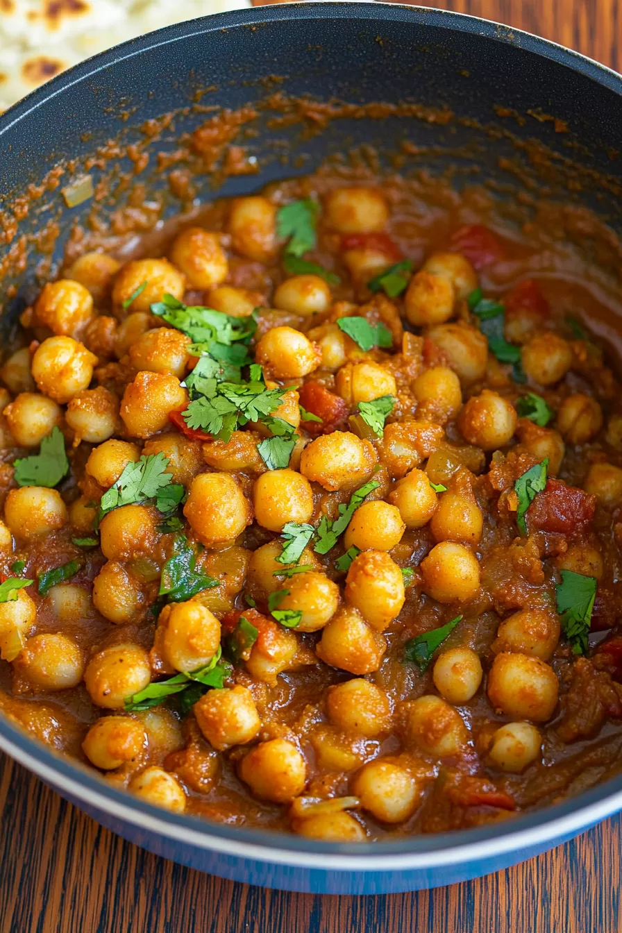 Close-up of tender chickpeas cooked in a flavorful tomato-based curry.