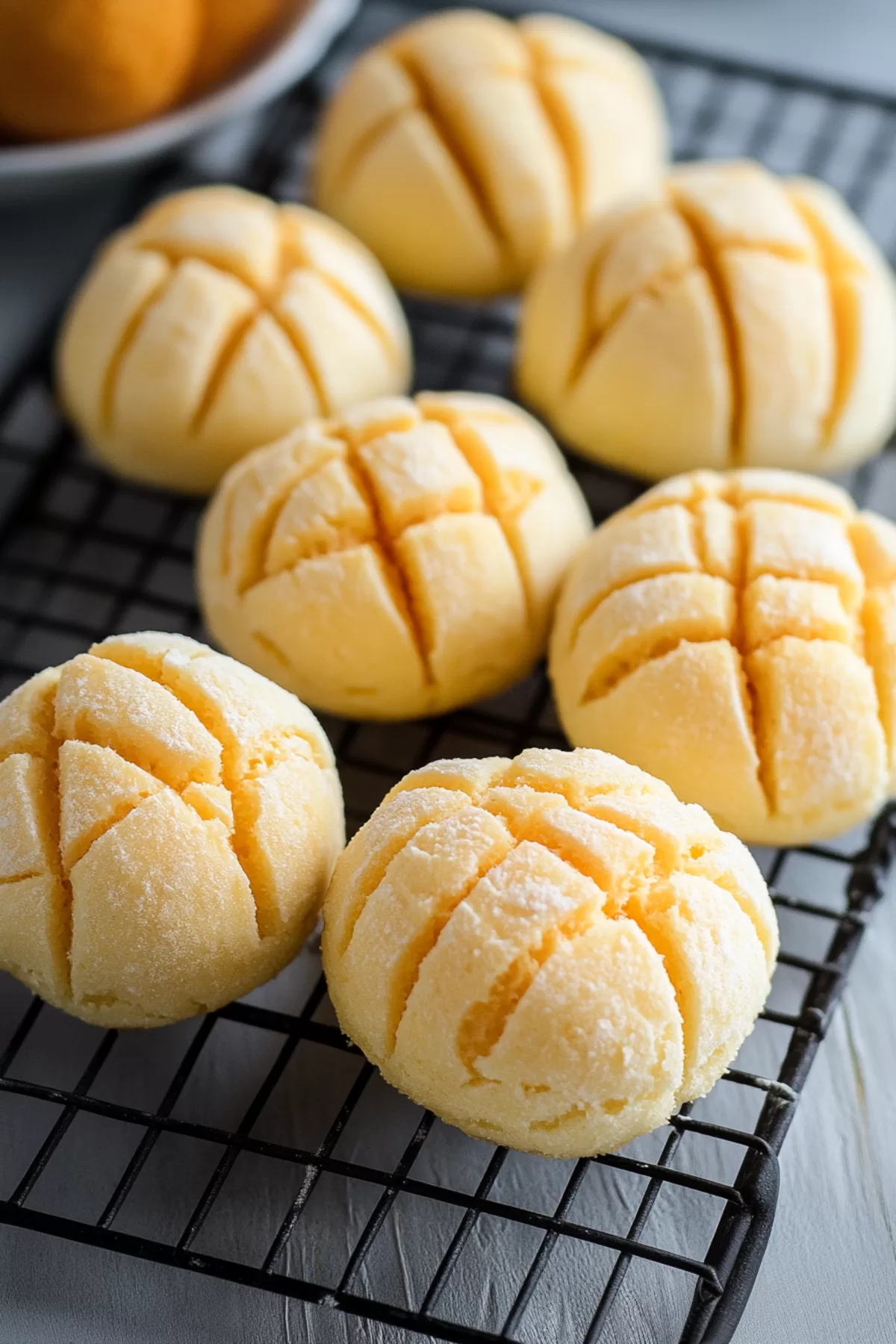 A tray of perfectly baked bread rolls with a lightly sugared finish.