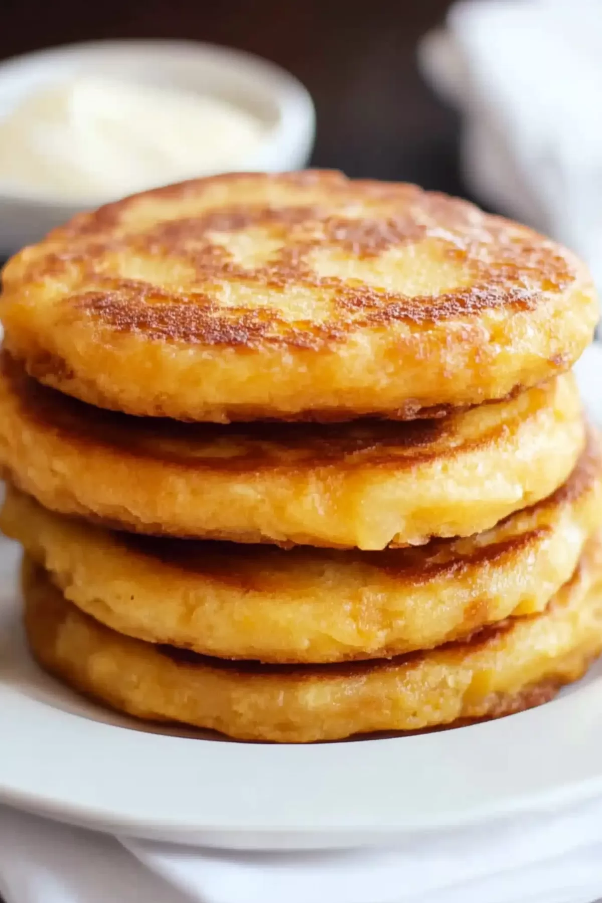 A close-up of golden brown, fluffy pancakes stacked neatly on a plate, ready to be served.