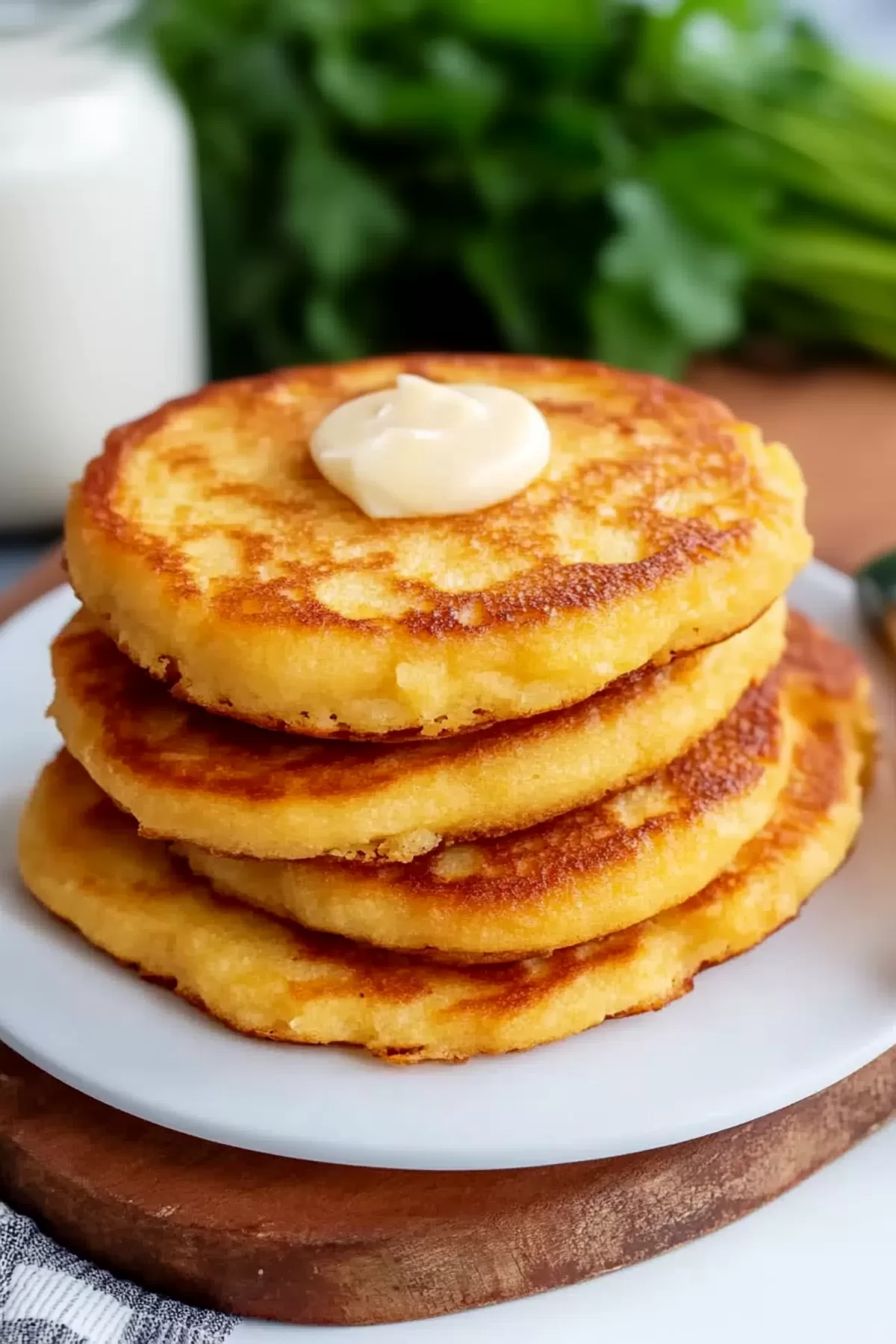 Cornmeal griddle cakes served with a dollop of butter, placed next to a fresh parsley garnish.