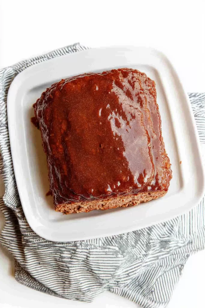 A perfectly glazed meatloaf resting on a plate, showcasing a rich caramelized finish.