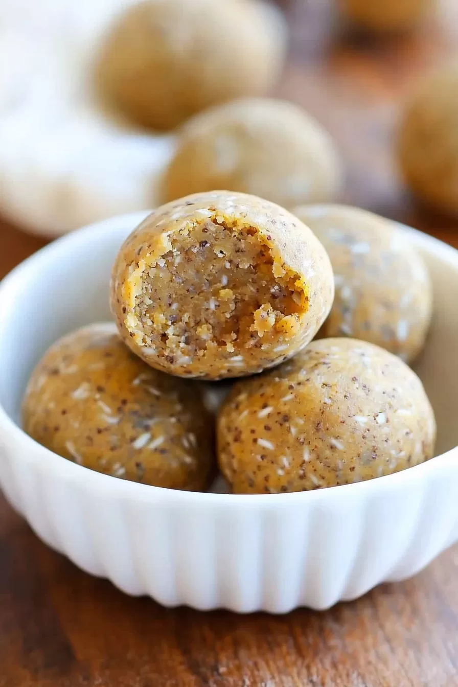 Round energy bites with a sprinkle of cinnamon on a rustic plate.