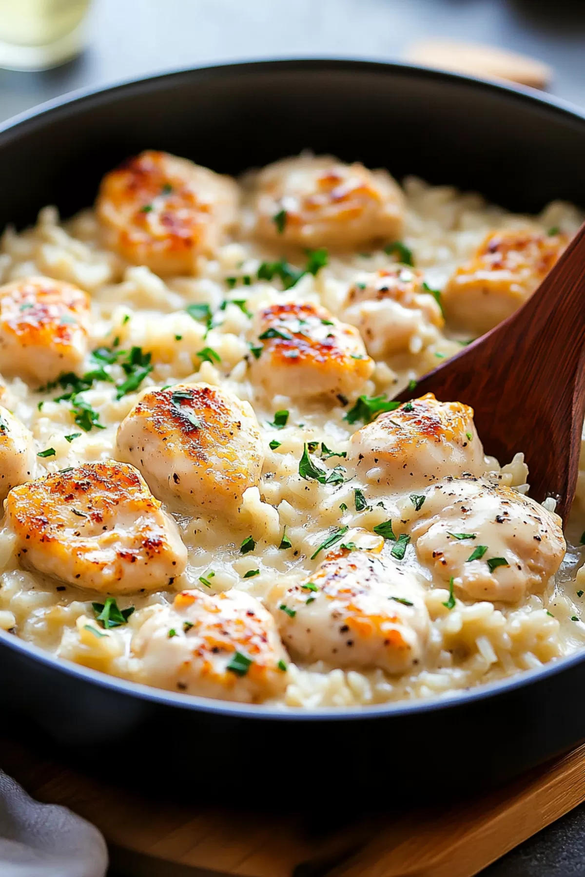 A serving spoon lifting creamy rice and chicken from the skillet, showcasing the rich sauce.