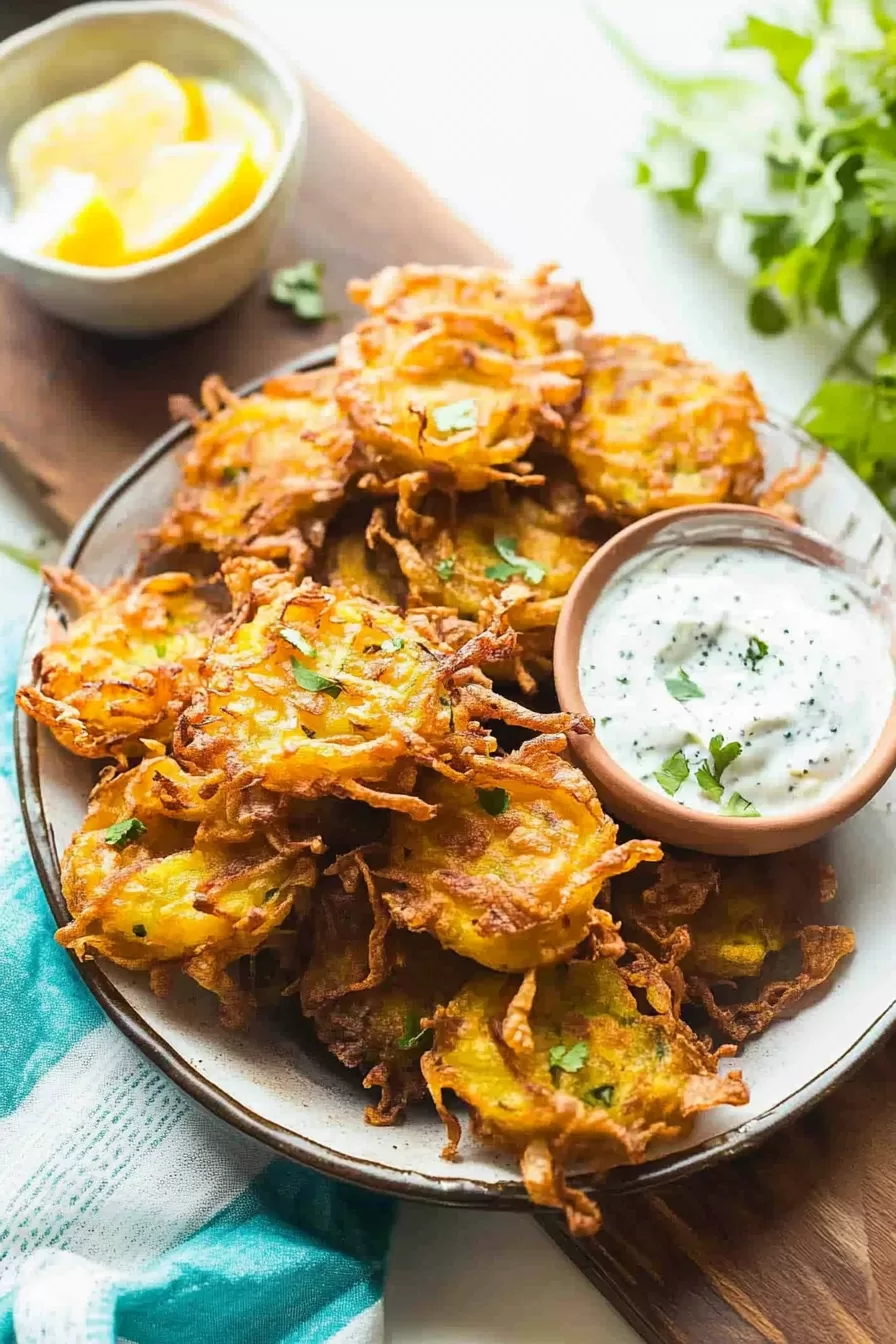 A plate of warm, crispy onion bites paired with a tangy yogurt dipping sauce.