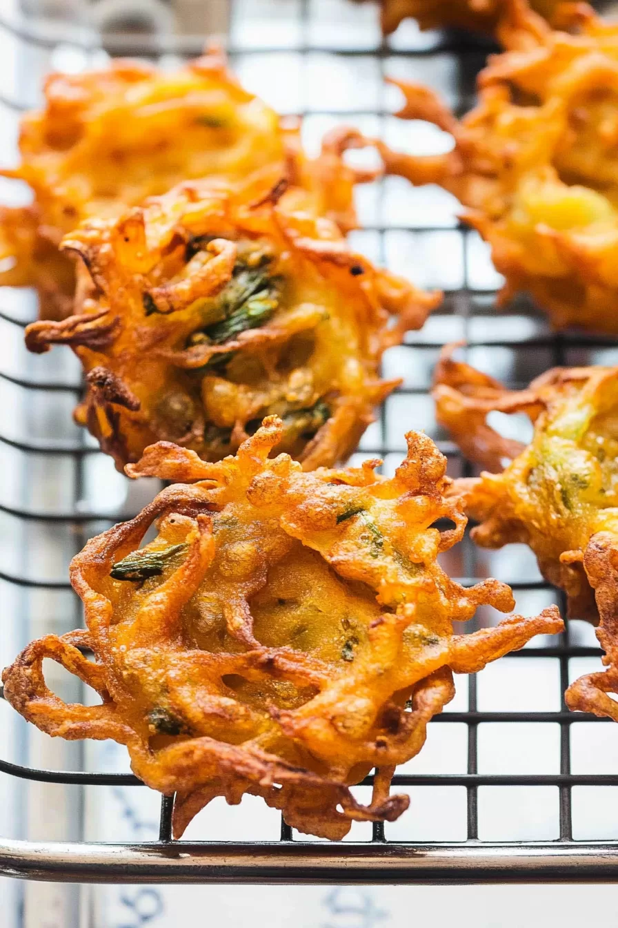 Golden onion fritters stacked on a platter, showcasing their crunchy, spiced texture.